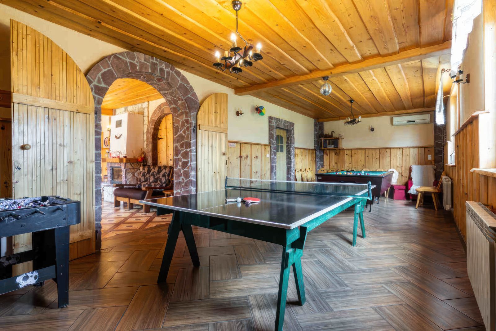 Sala rekreacyjna Willi OdNova z stołem do ping-ponga, kominek, drewniany sufit i kamienne łuki